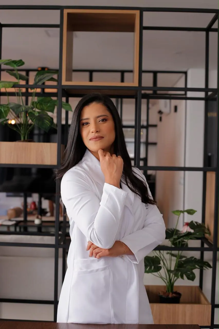 Daiane Oliveira de jaleco branco no consultório