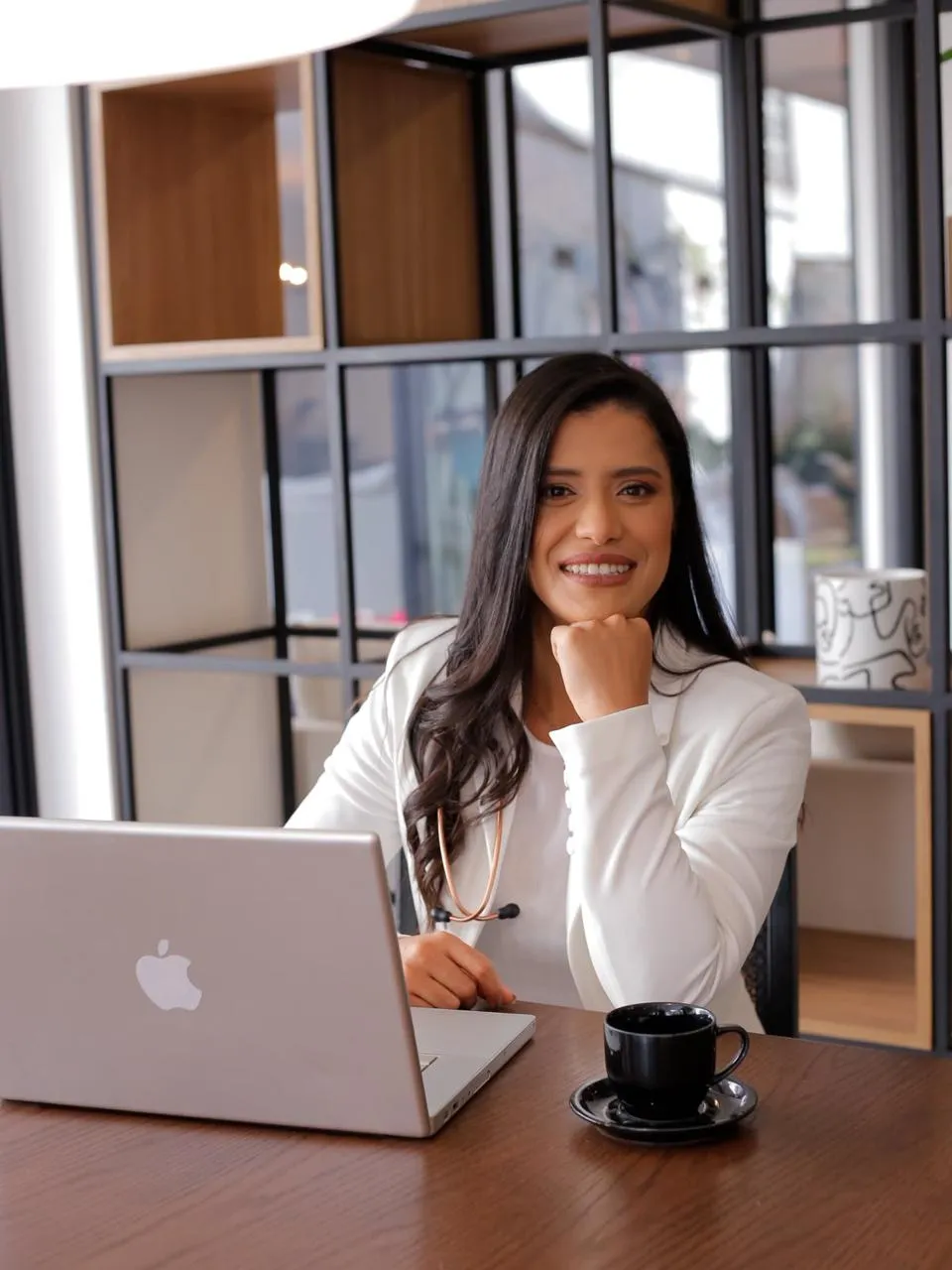 Daiane Oliveira, fisioterapeuta, sorrindo à mesa do consultório